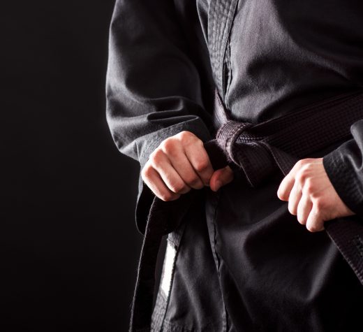 Closeup of male karate fighter tying the knot to his black belt